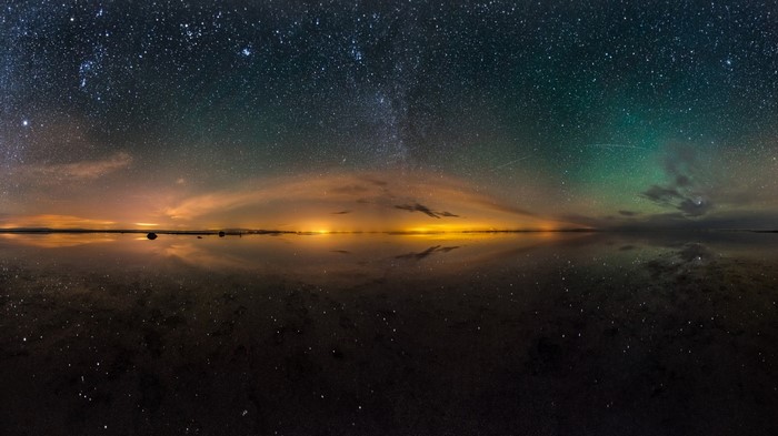 Starry night sky over a reflective landscape with aurora