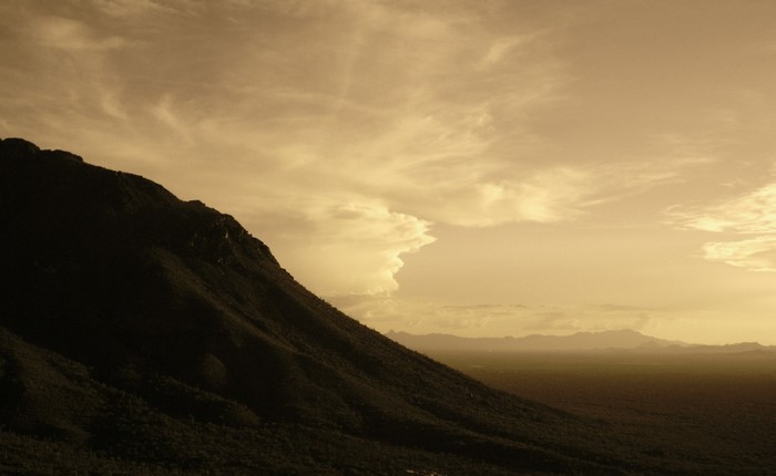 Mountain slope against a cloudy sky at sunset