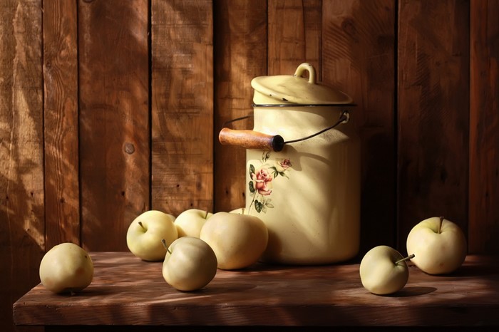 Still life of apples and a painted milk can