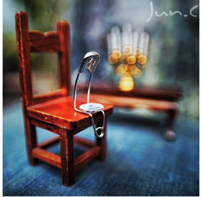 Safety pin on a miniature chair with bokeh background