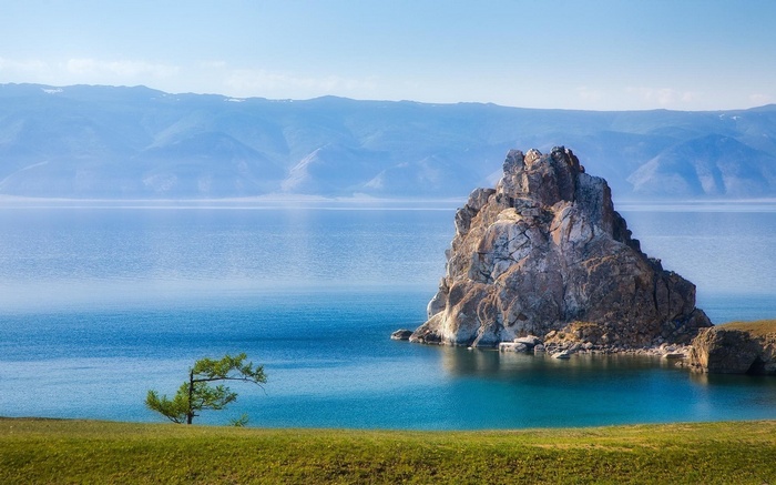 Rock formation in a lake with mountains in the background