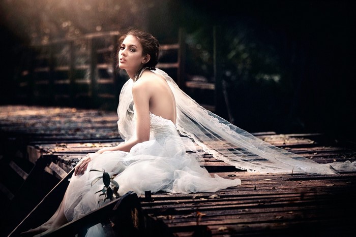 Woman in a white dress on a wooden bridge