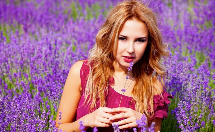 Woman in a lavender field holding a flower