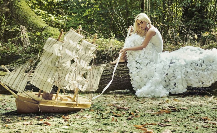 Woman in white dress with model ship in forest