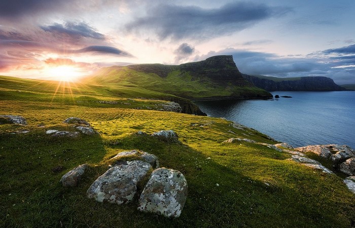 Sunlight over a green coastal landscape in Scotland