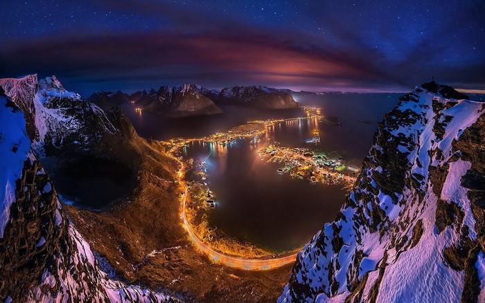 Night view of Lofoten Islands with snow-capped mountains and village lights