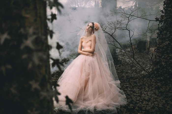 Woman in a pink wedding dress and veil in a forest