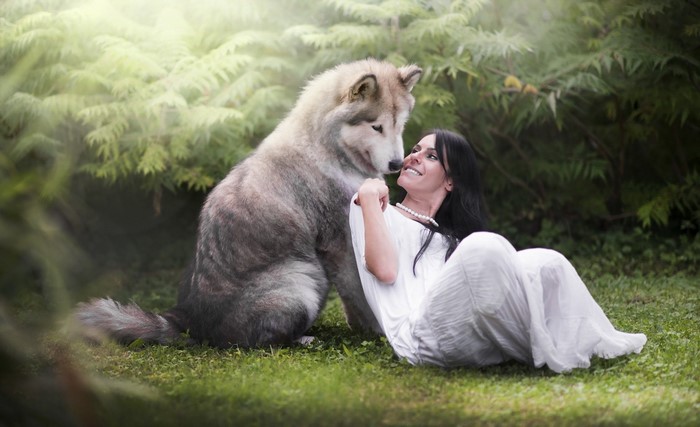 Woman in white dress with large dog in forest