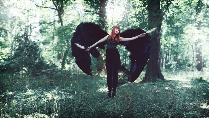 Woman with black wings in a forest