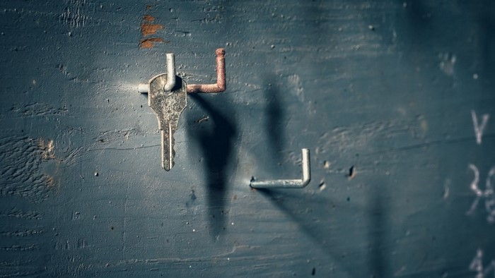 Key hanging on a rusty hook on a blue wooden wall