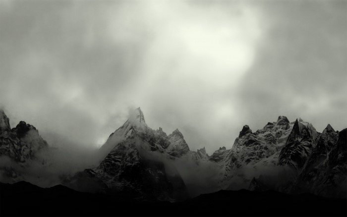 Monochrome mountain range shrouded in mist and clouds