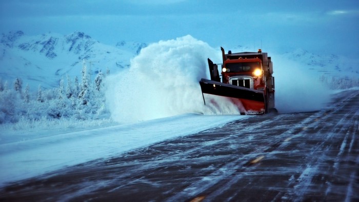 Snowplow clearing a snowy road in winter mountains