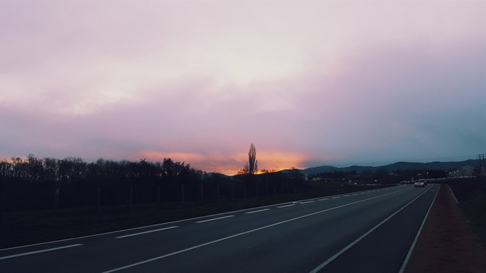 Road at sunset with trees and mountains