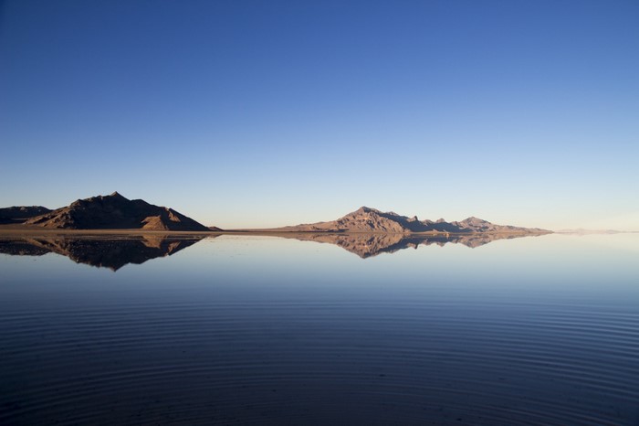 Mountains reflected in a calm body of water under a clear sky