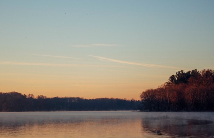 Misty lake at sunrise with forest and sky