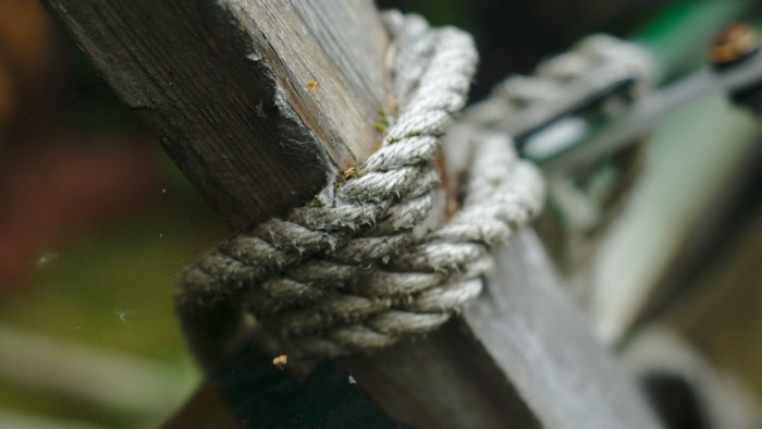 Close-up of a thick rope tied around wooden posts