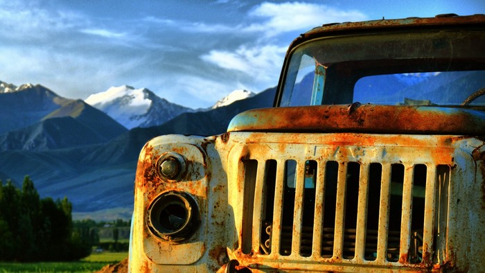Rusted truck in front of snow-capped mountains