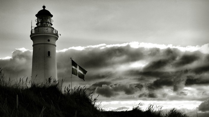 Lighthouse and Danish flag on a cloudy day