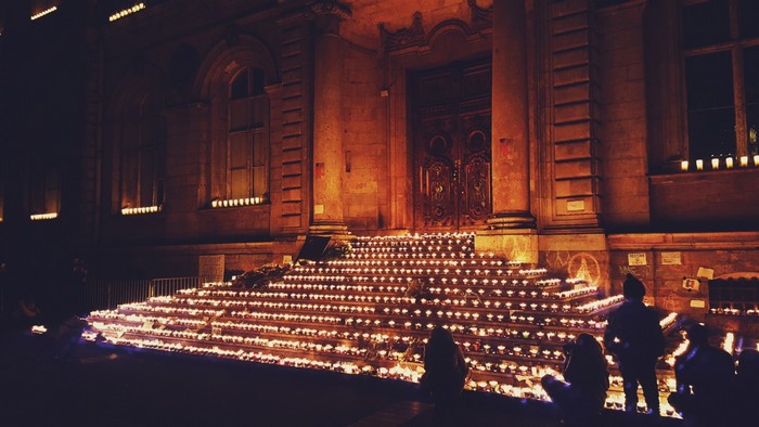 People sitting on steps lit by candles at night