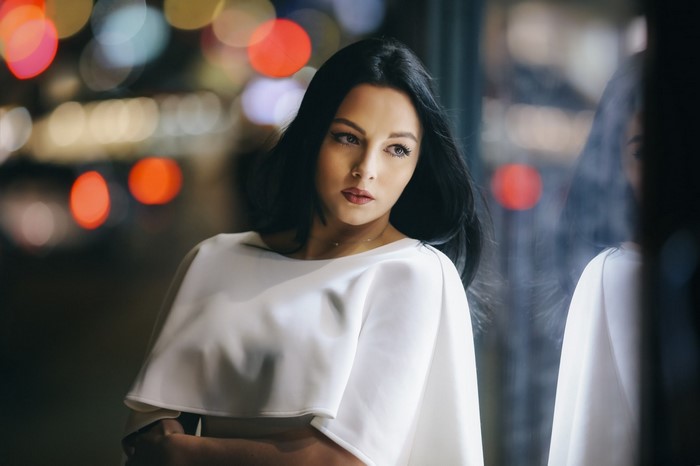 Woman in white dress looking away with bokeh lights
