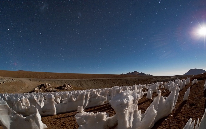 Night sky over icy formations in a desert landscape