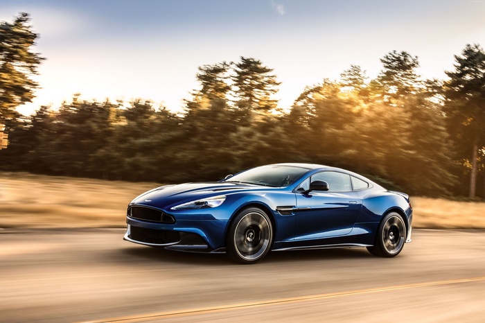 Blue Aston Martin Vanquish driving on a road