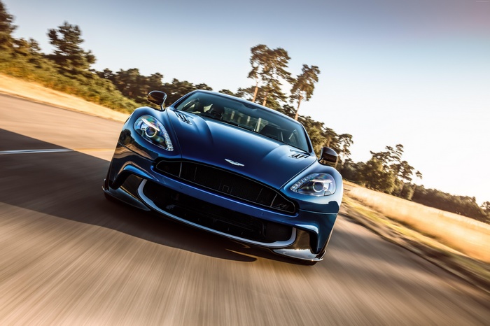 Blue Aston Martin Vanquish driving on a road