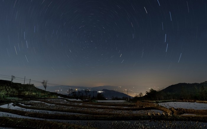 Star trails over terraced fields at night