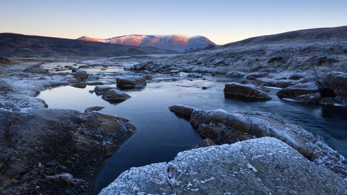 Frosty river flowing through a rocky landscape at sunrise