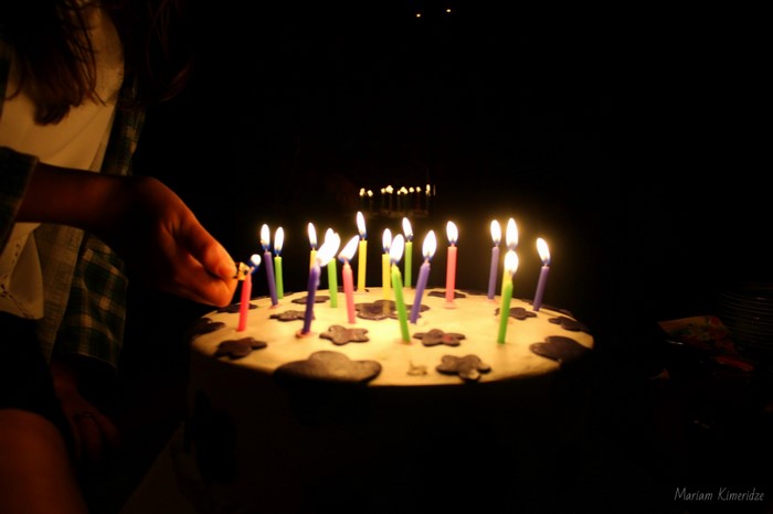 Person lighting birthday cake candles at night