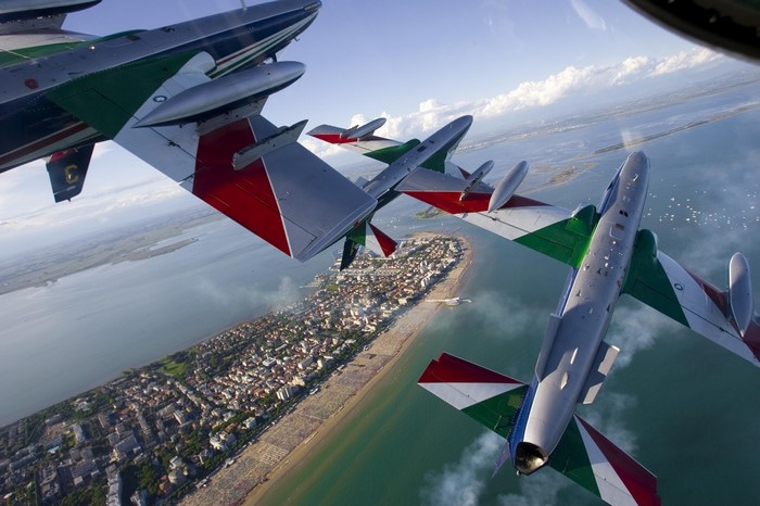 Frecce Tricolori aerobatic team flying over a coastal town