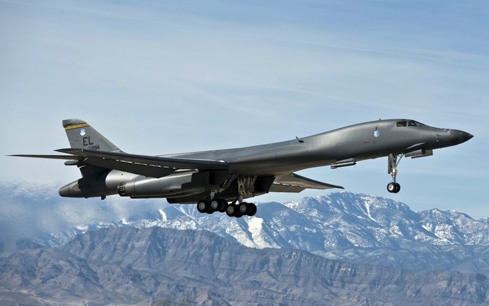 Rockwell B-1 Lancer bomber flying over mountains