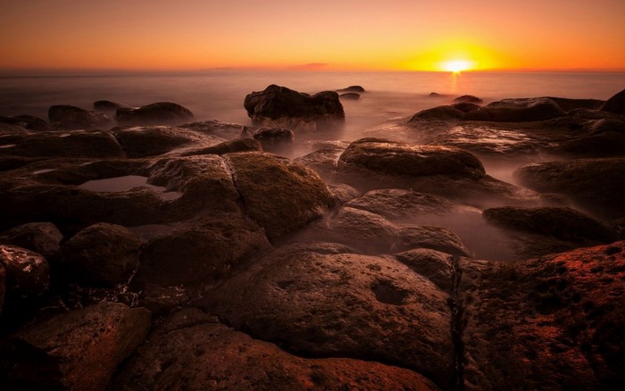 Sunset over rocky shore with ocean waves
