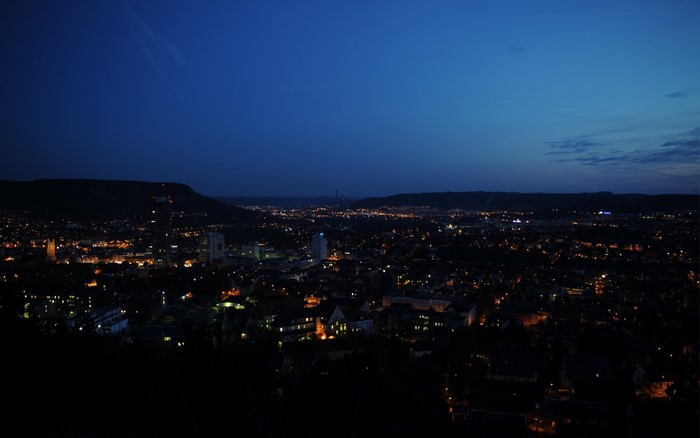 Cityscape at dusk with distant lights and hills