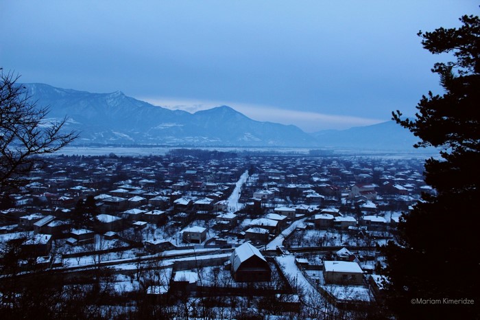 Snowy village in Georgia at dusk with mountains