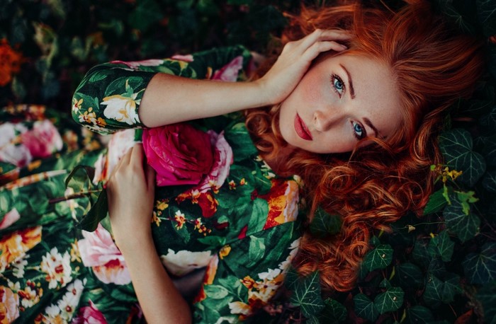 Redhead woman in floral dress holding a rose