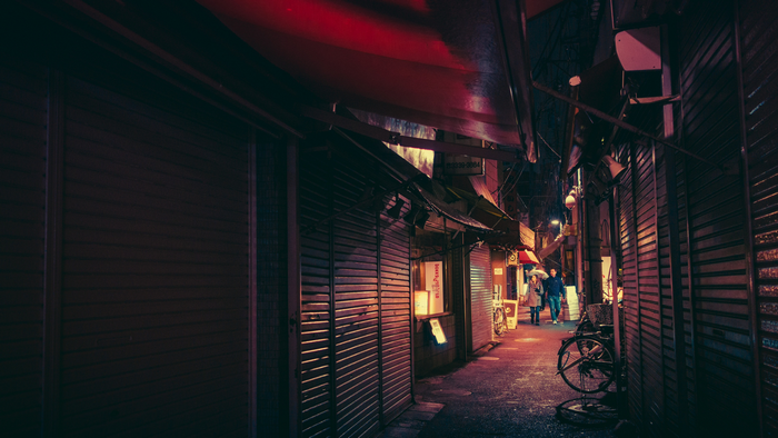 Night alley with closed shops and people walking