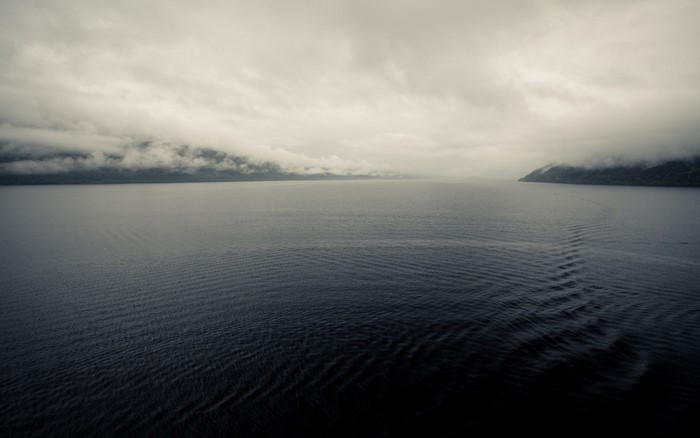 Misty lake with distant foggy mountains and waves