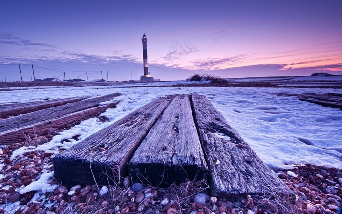 Winter landscape with lighthouse at sunset