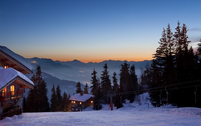 Mountain landscape with chalets and ski lift at dusk
