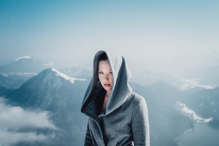 Woman in a grey hood in the mountains