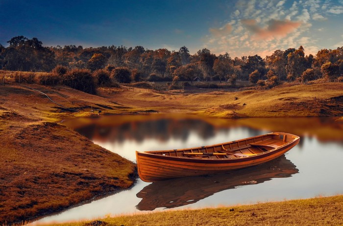 Wooden boat on a calm lake at sunset