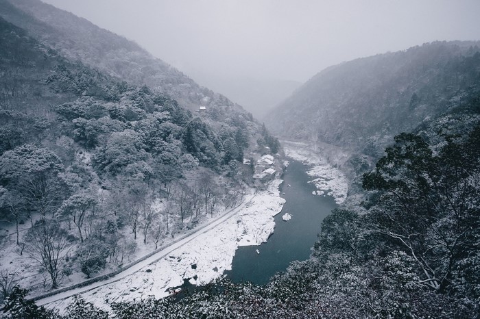 Snowy mountain valley with a river and trees