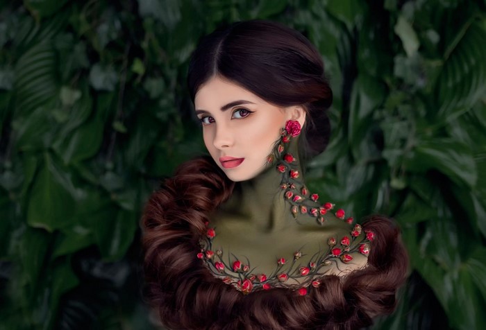 Woman with roses and dark hair against green foliage
