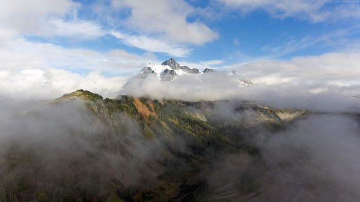 Snow-capped mountains shrouded in clouds and fog