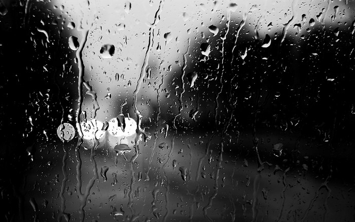 Monochrome rain on glass with blurred lights