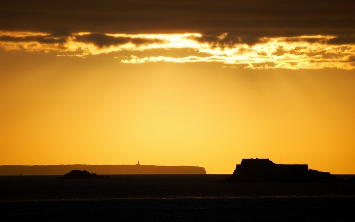 Sunset over the sea with islands and lighthouse