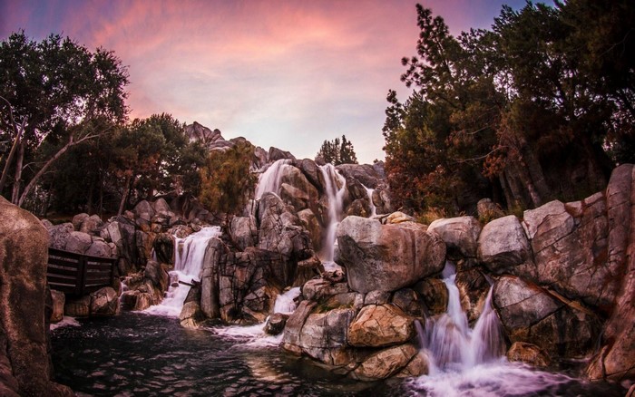 Waterfall cascading over rocks with trees and sunset sky