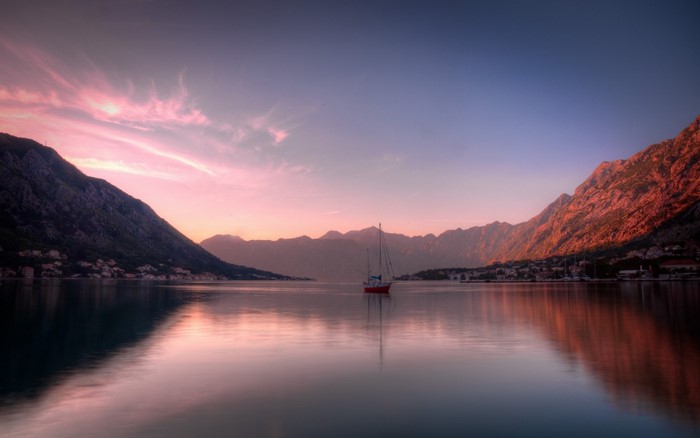 Sailboat on a calm bay with mountains at sunset