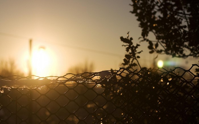 Sunset over a chain-link fence with snow